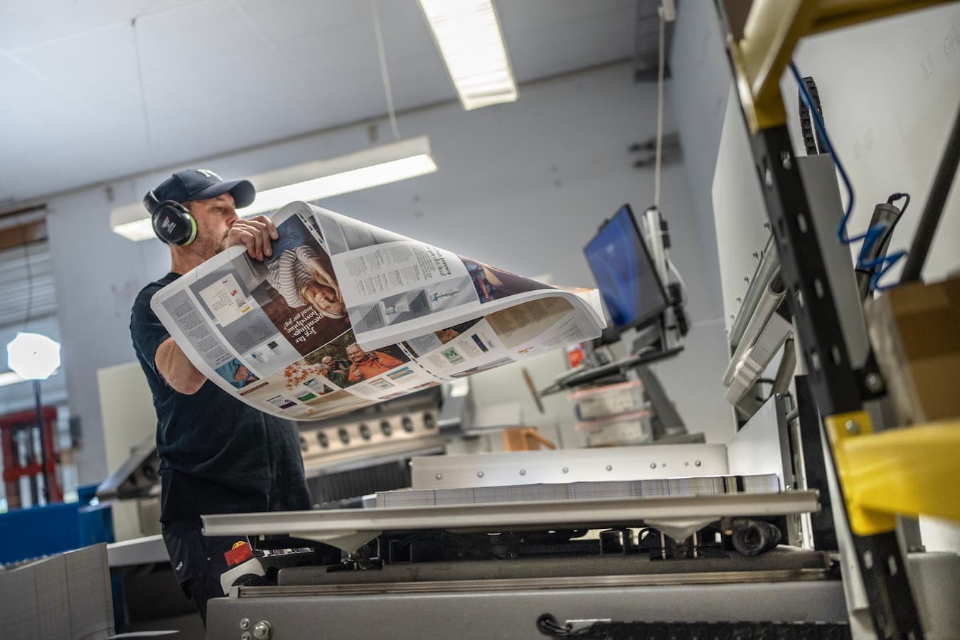 Medarbejder efterbehandler trykte materialer i produktionen