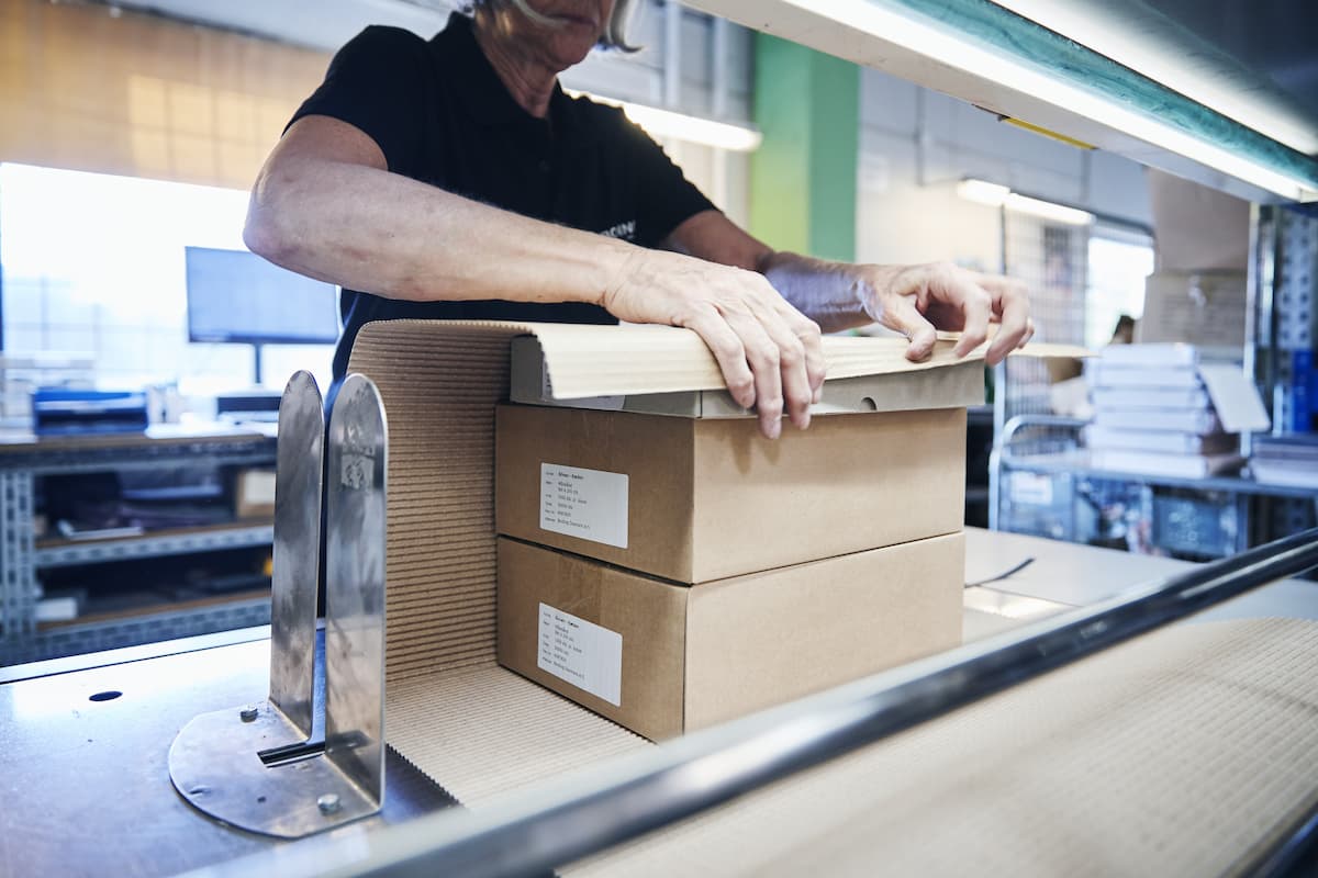 Medarbejder pakker varer i papkasser hos Bording før distribution.